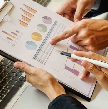 Business concept. Business people discussing the charts and graphs showing the results of their successful teamwork. Selective focus.